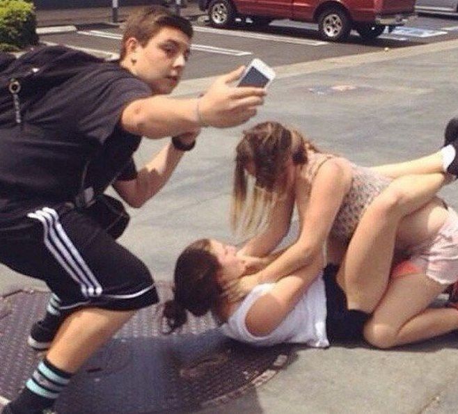 guy taking a selfie with girls fighting