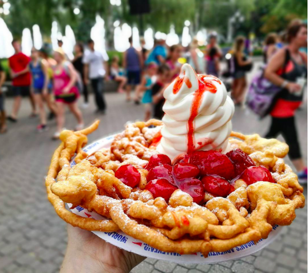 Funnel Cake
The concept of the Funnel Cake dates back to early medieval Arabic and Persian cultures, where a similar dough was excreted through a funnel into hot oil to create a lattice, and cooked.
Later on, German immigrants brought over the concept in the 1800’s, using the more common baking soda dough and garnishing it with fruit.
Now, we devour it, covered in strawberry sauce and soft serve. It’s a very share-able treat, but I don’t know how many people actually do. It’s too good to share.