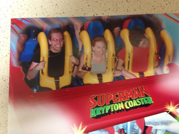 While the guy and the girl look like they’re having the time of their lives on the Superman Krypton Coaster at a well-known theme park, the guy on the right, in the red t-shirt, looks like his head is about to fall clean off his shoulders.