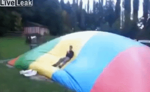 man getting knocked into the air from an inflatable bouncy thing