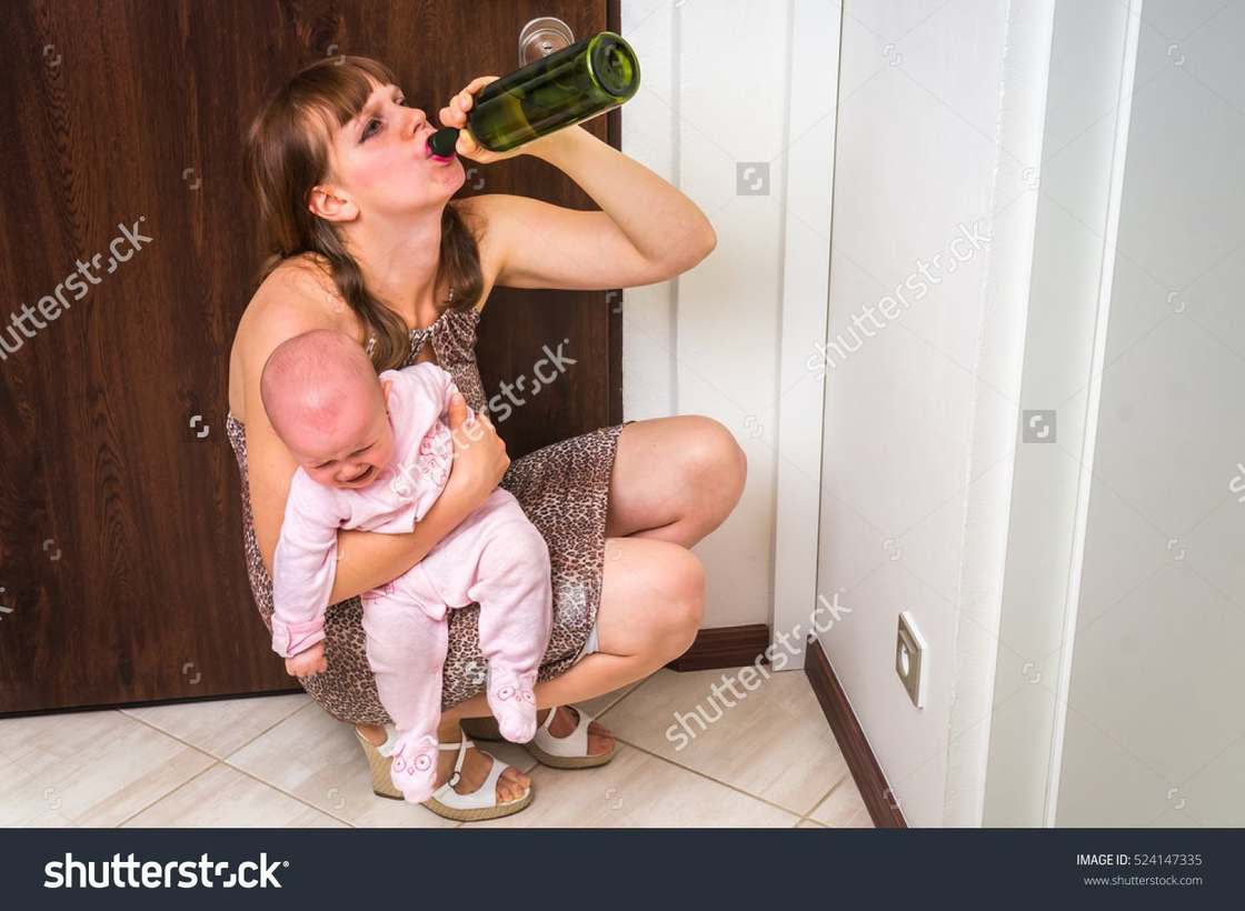 WTF stock photo of mother with baby on floor drinking alcohol from the bottle.