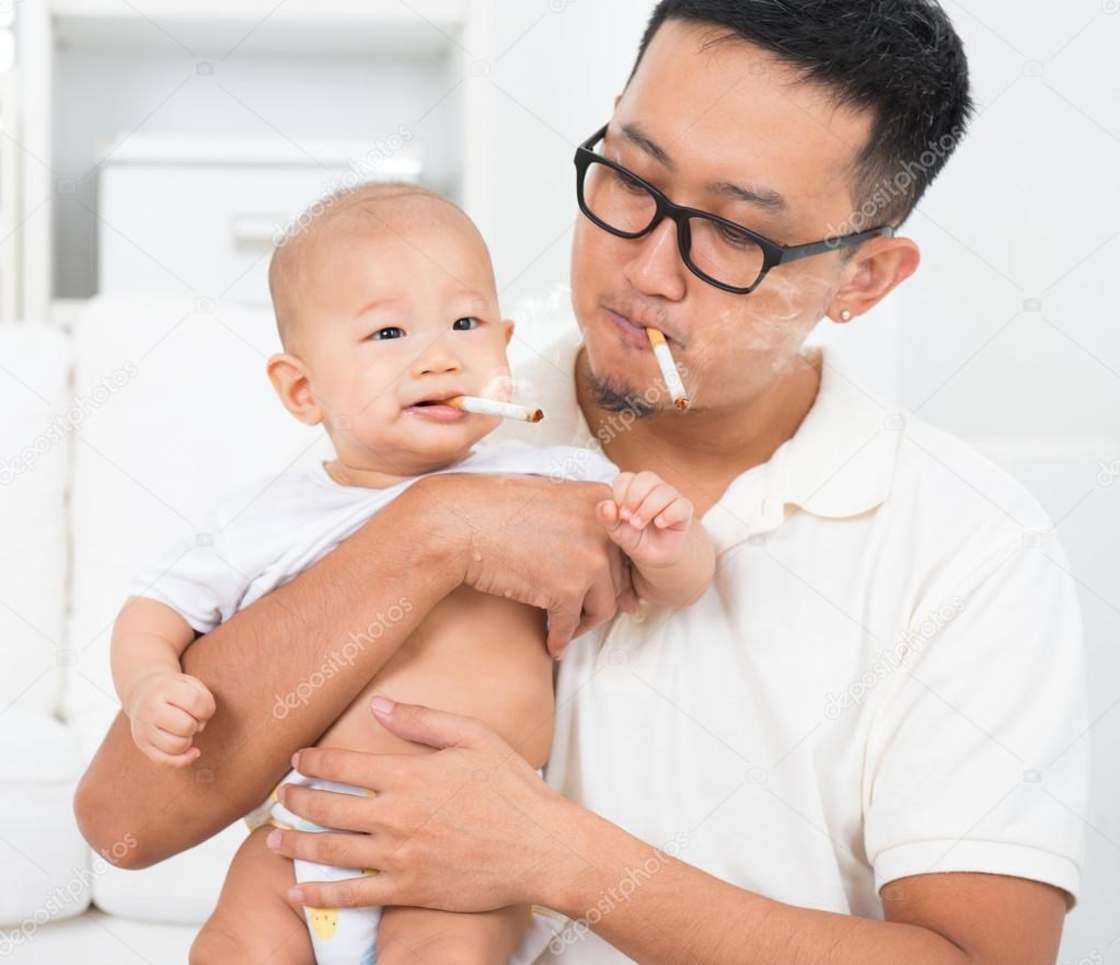 Parent and son of Asian origin smoking cigarettes together