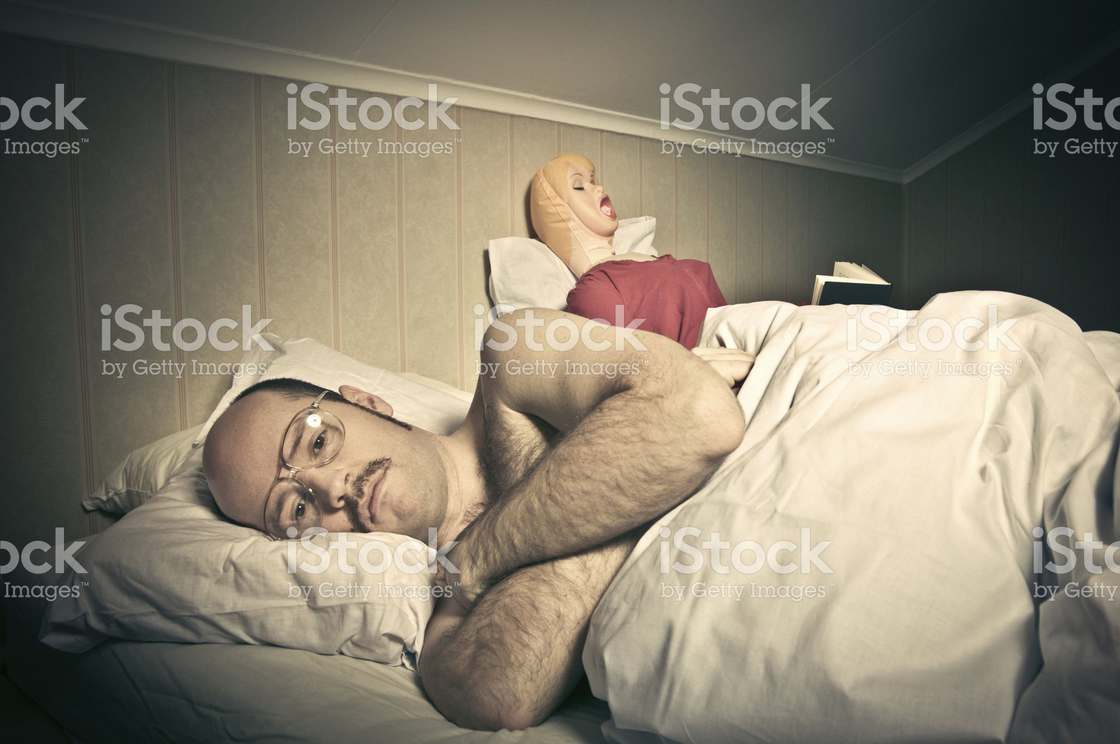 Man angry in bed as woman is sitting up behind him
