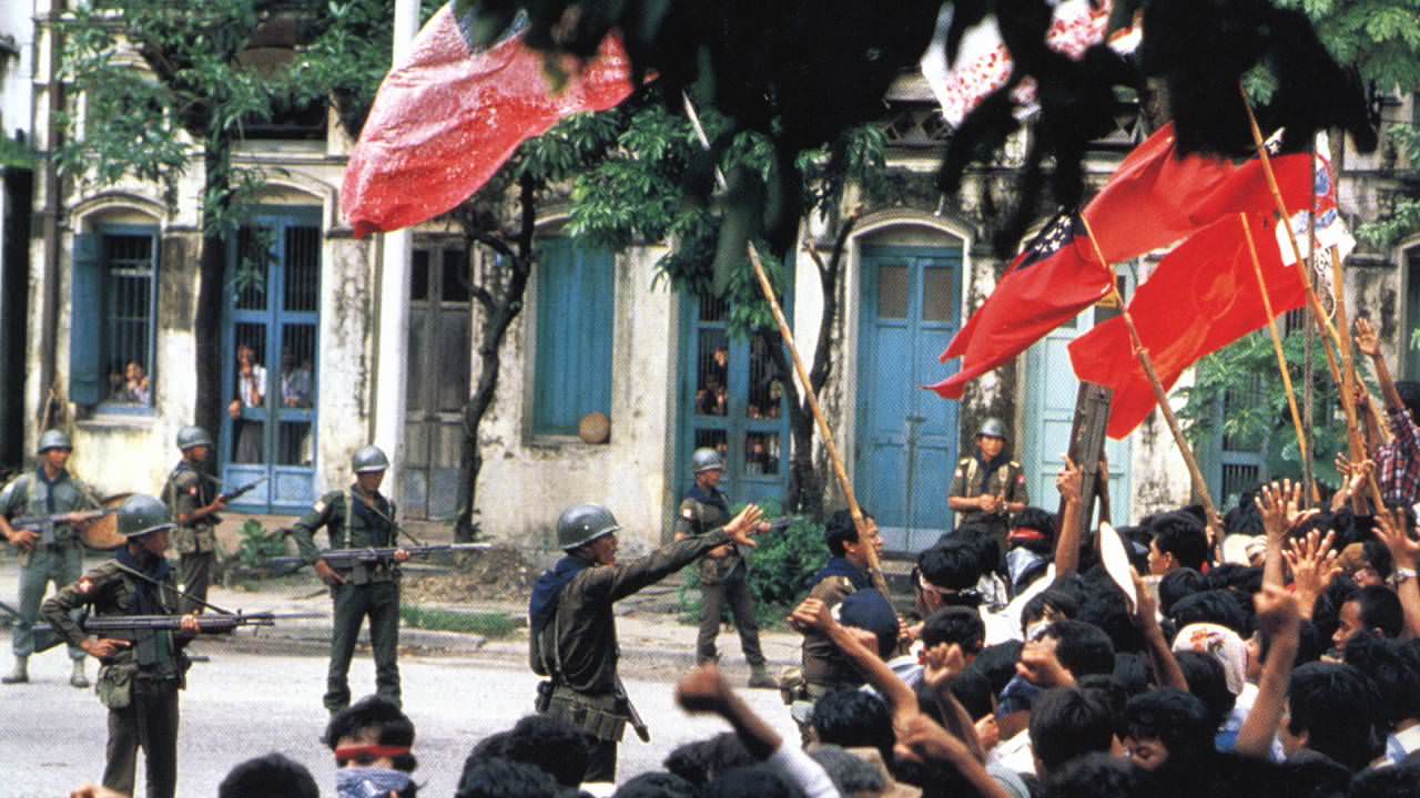 Protesters are confronted by the military in Burma (now Myanmar) in 1988. This was part of the 8888 Uprising, which had over 2 million civilians take part in. It started with student protests, and saw monks and civilians join in huge numbers. Like similar movements around the world, these were pro-democratic movements, demanding changes. And also like similar movements especially in Asia at the time, the response from the government was brutal. Sometime after this picture was taken, the soldiers would fire into the crowd. At major demonstrations around the country, similar actions took place. The government soldiers killed up to 10,000 people, wounding countless more. Tens of thousands of people fled, joining insurgent groups in neighboring countries to fight back.