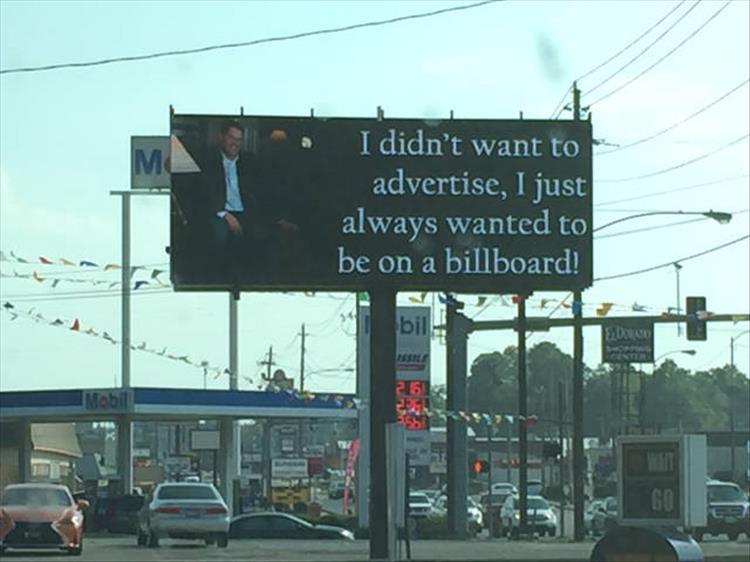 such a random picture of a billboard next to a mobil gas station of someone who didn't want to advertise but always wanted to be on a billboard