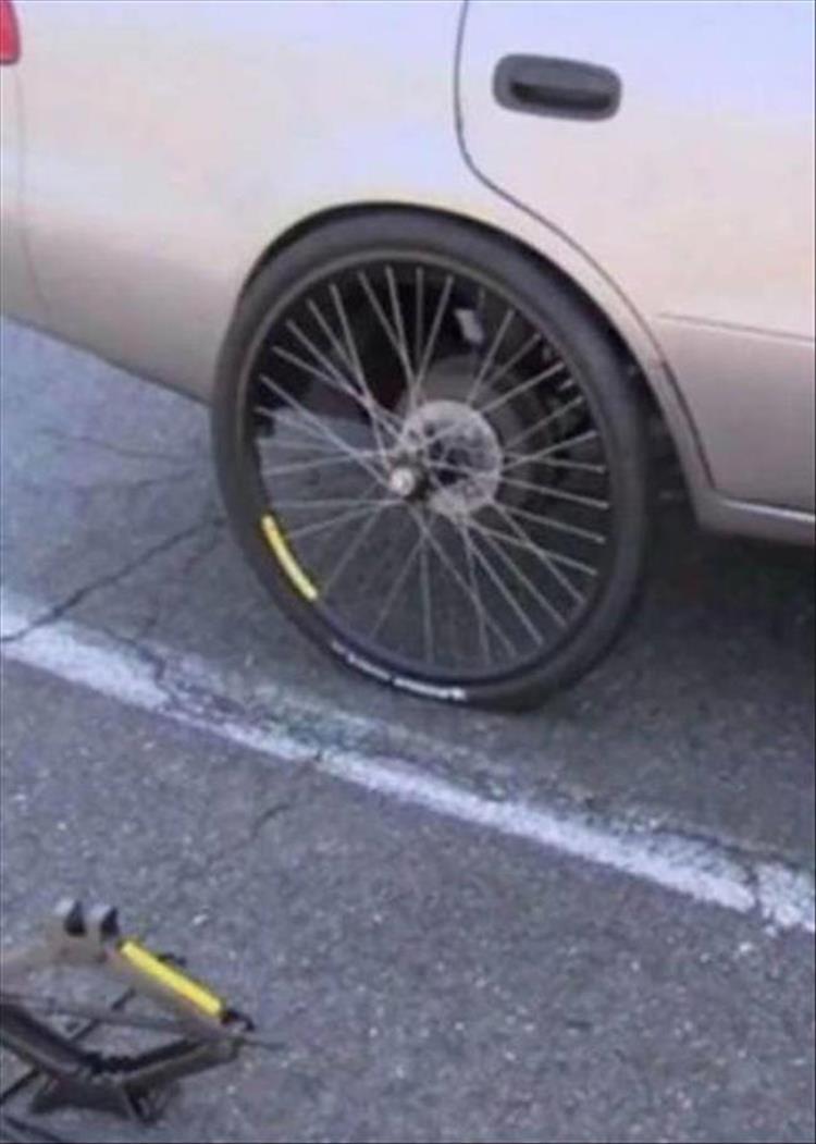 funny random picture of bicycle wheel on a car rear wheel and a car jack off to the corner