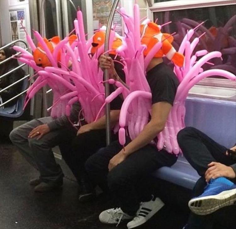 random picture of 3 men dressed in balloons on the subway to look like fish or flamingos