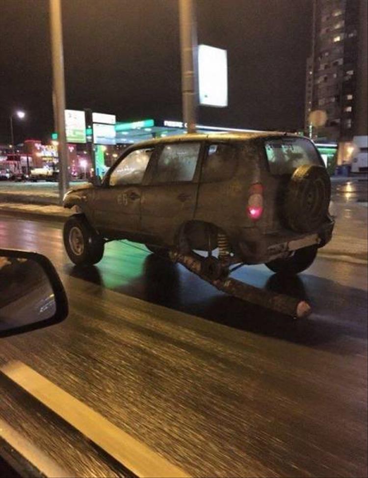 random funny picture of a car missing a wheel using a log instead