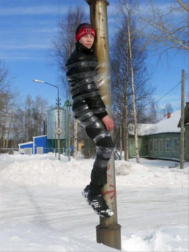 random picture of dude taped to a metal pole in a snowy environment