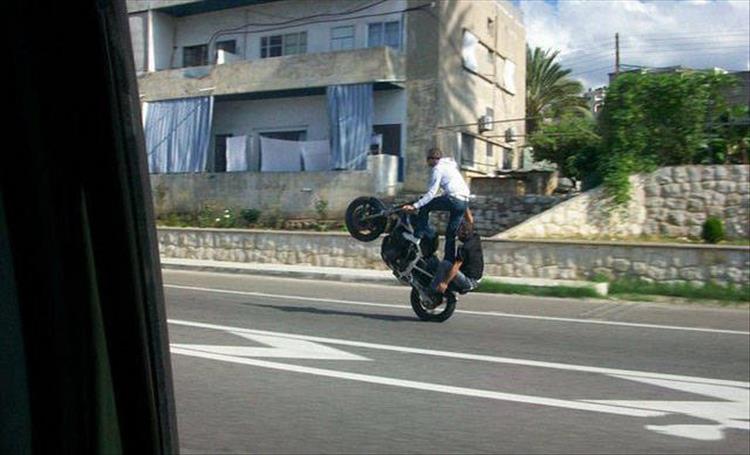 random picture of 2 people riding a motorcycle doing a wheelie