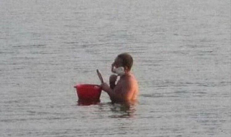 random picture of some one in the sea shaving with a red bucket