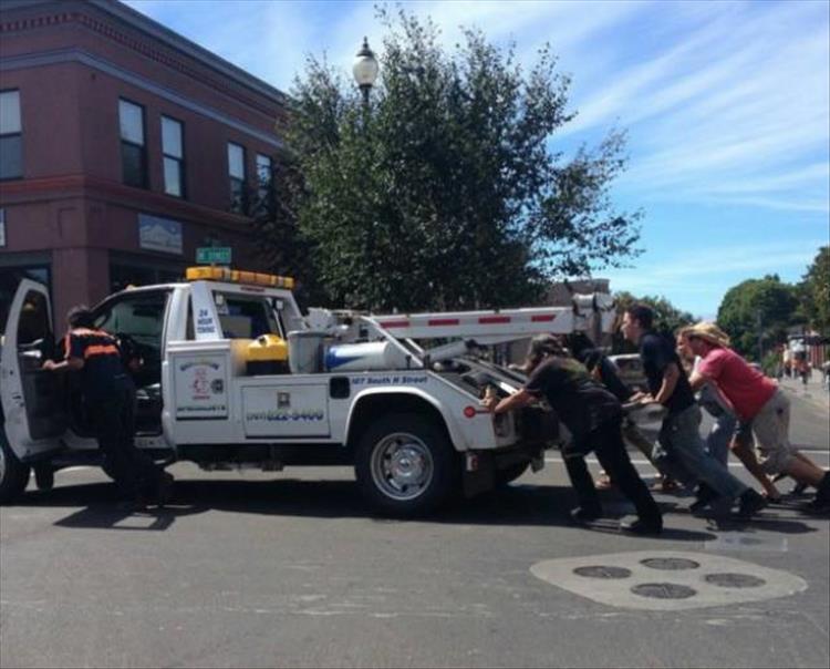 random picture of people pushing a broken down tow truck