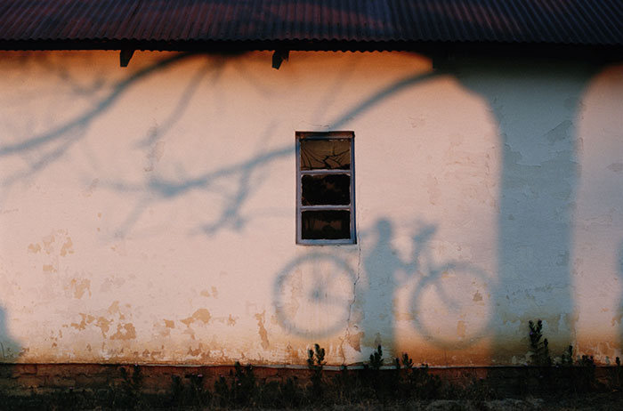 A shadow of a man holding a bicycle is cast on a wall near the Zambezi River, 1996Image source: Chris Johns