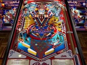 Harlem Globetrotters on Tour (1979)This pinball game is arguably the most popular sports-styled pinball game of all time. Artwork features cool caricatures of the team on the backglass and a patriotic red, white, and blue color scheme. Some of the playfield features are three flippers – one on the right, two on the left and three pop bumpers. The design is fairly simple, but the game is a lot of fun for pinball collectors and Globetrotter fans.