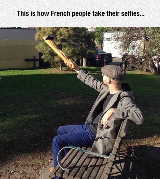 French person taking a selfie using a baguette to hold up the phone.