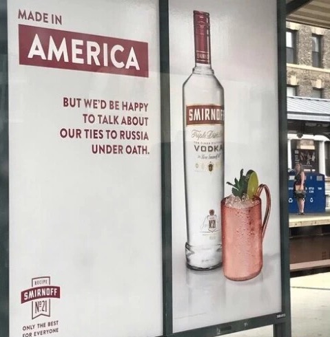 Funny advertisement in a bus stop of Smirnoff vodka saying Made In America and Happy to Talk under Oath about their ties to Russia.