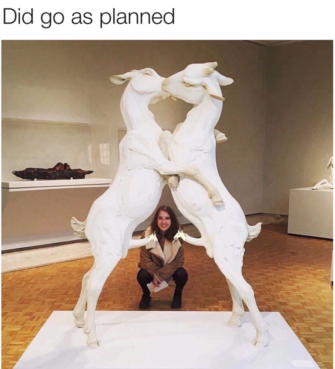 Girl taking her picture with a statue of two male goats making out in front of her