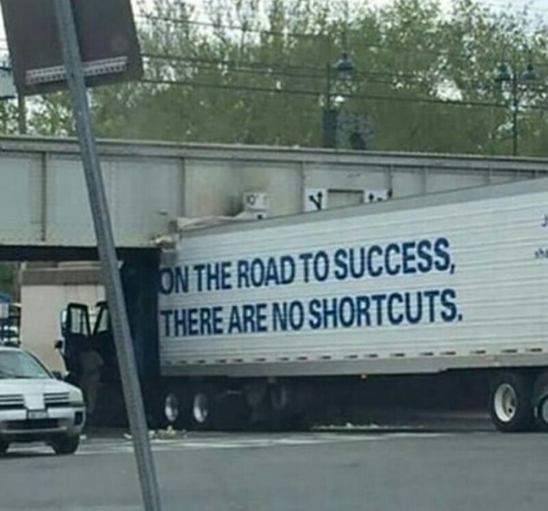 Truck that says the road to success has no short cuts that got stuck on a low underpass, probably trying to take a shortcut.