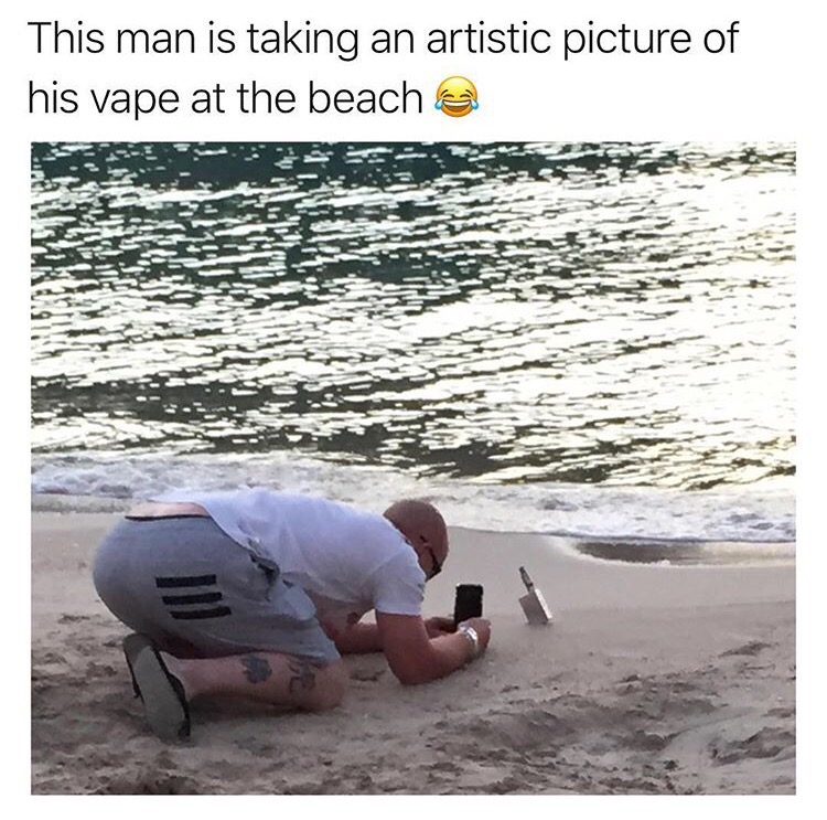 we get it you vape - This man is taking an artistic picture of his vape at the beach