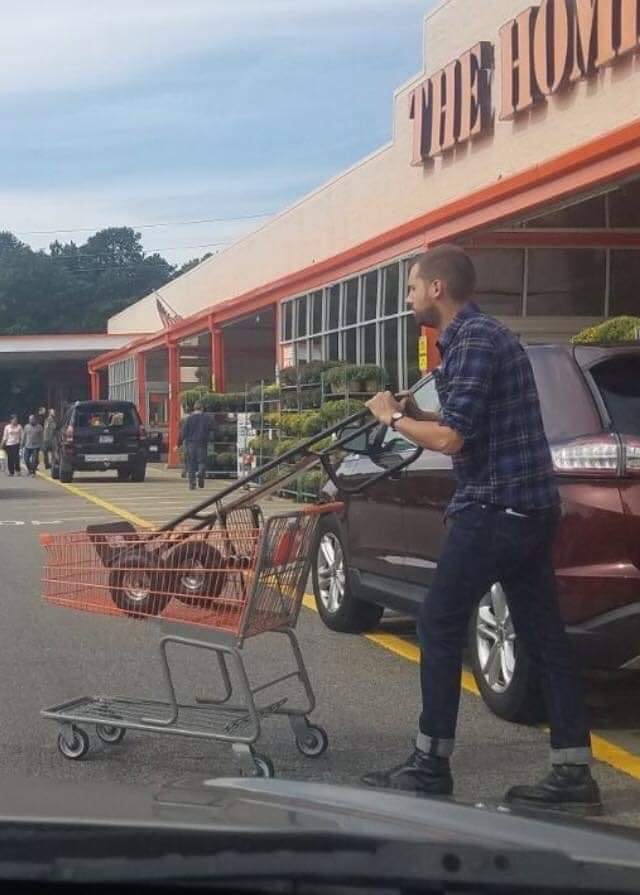 man using a shopping cart to bring a hand truck dolly to his car
