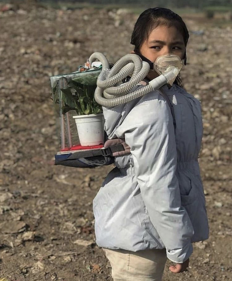 girl wearing mask hooked up to container holding plant