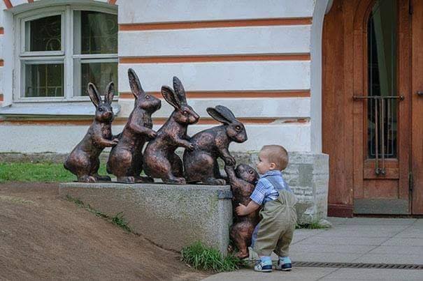 kid posing with bunny statues