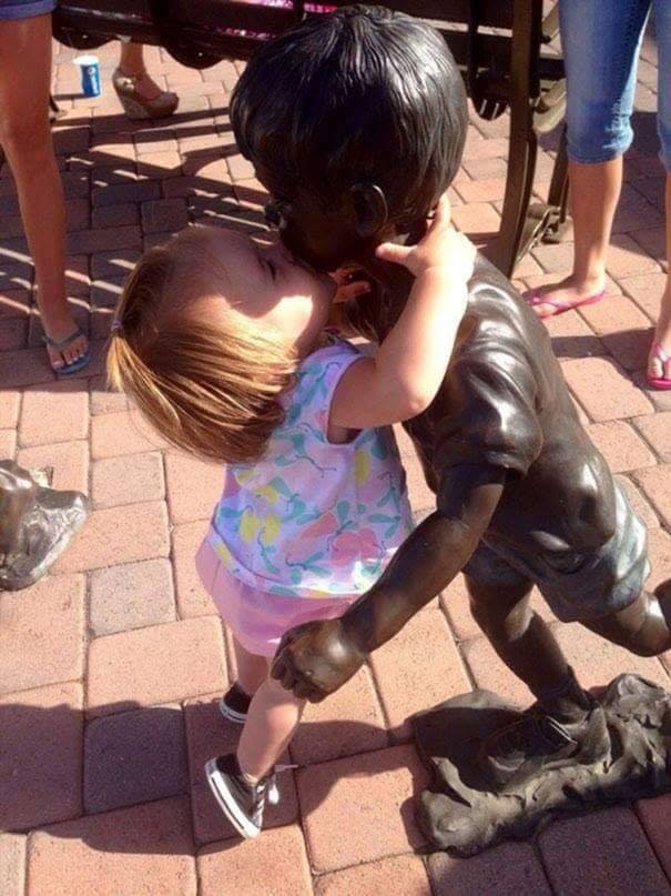 baby girl kissing statue of a boy