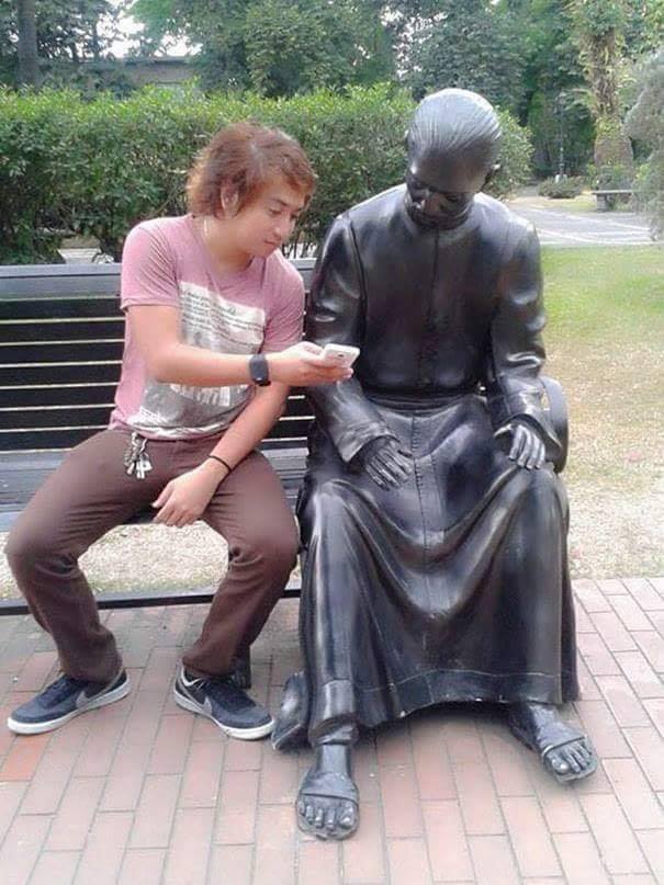 man showing his smart phone to a statue