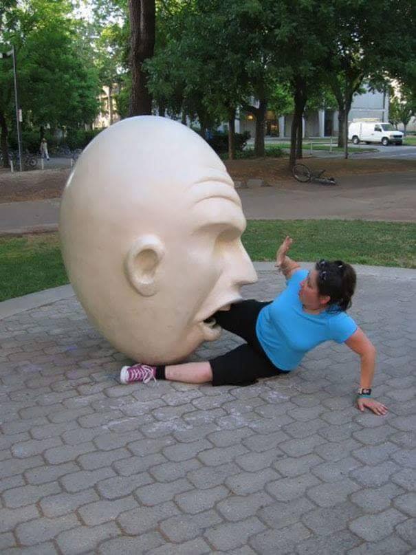 sculpture of an egg head eating a man