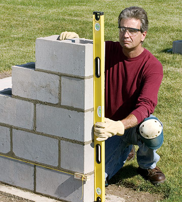 Building end leads: Step 4

Build up the lead on one end of the footing by throwing mortar for the second course and starting this course with a half block. Butter the ears of the second block in this course and continue laying the block three or four courses high. Check often for level, plumb, and square. Periodically check the firmness of the mortar by pressing it with your thumb. When you can just dent it, stop setting block and strike the joints.