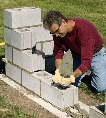 Building between the leads: Step 1

Stretch a line with mason's blocks between the leads. Set the line 1/16 inch from the face of the block and level with the top of the first course. Lay a mortar bed on the footing between the leads, and set the block, working from both sides to the center.