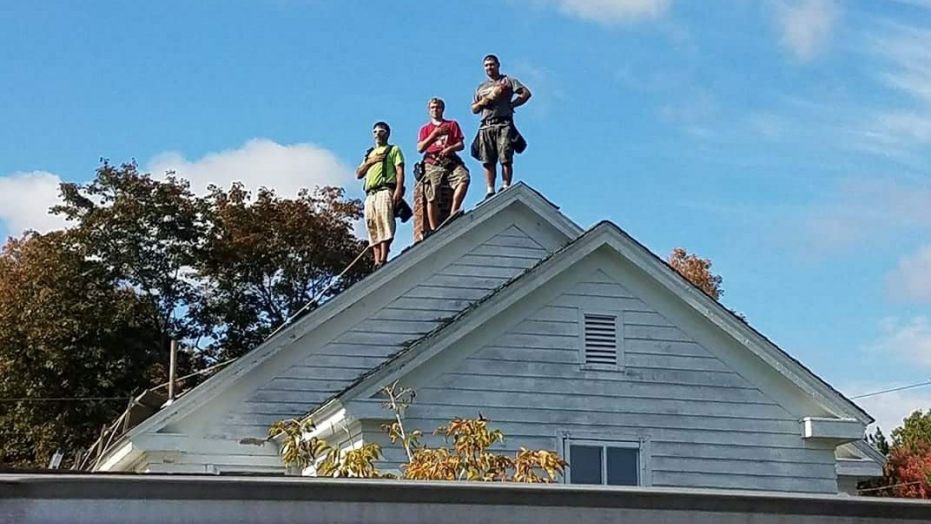 These roofers were working across the street from a high school where a football game was starting. As The National Anthem played, they chose to show their respect. Someone in the stands shot this picture.