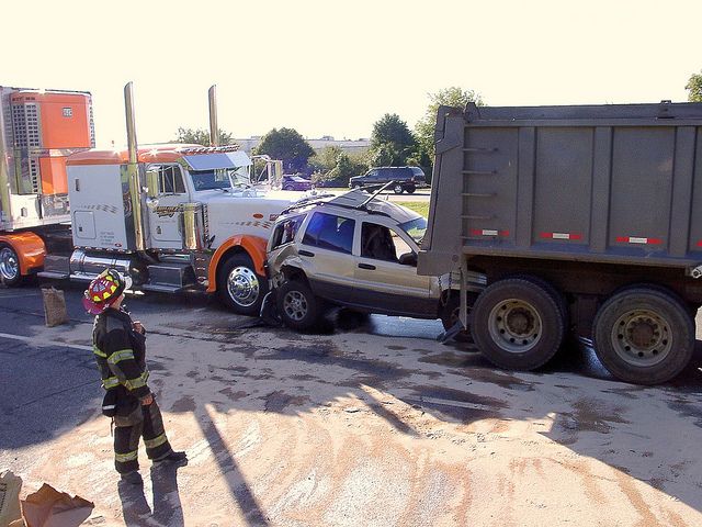 car crunched between two trucks