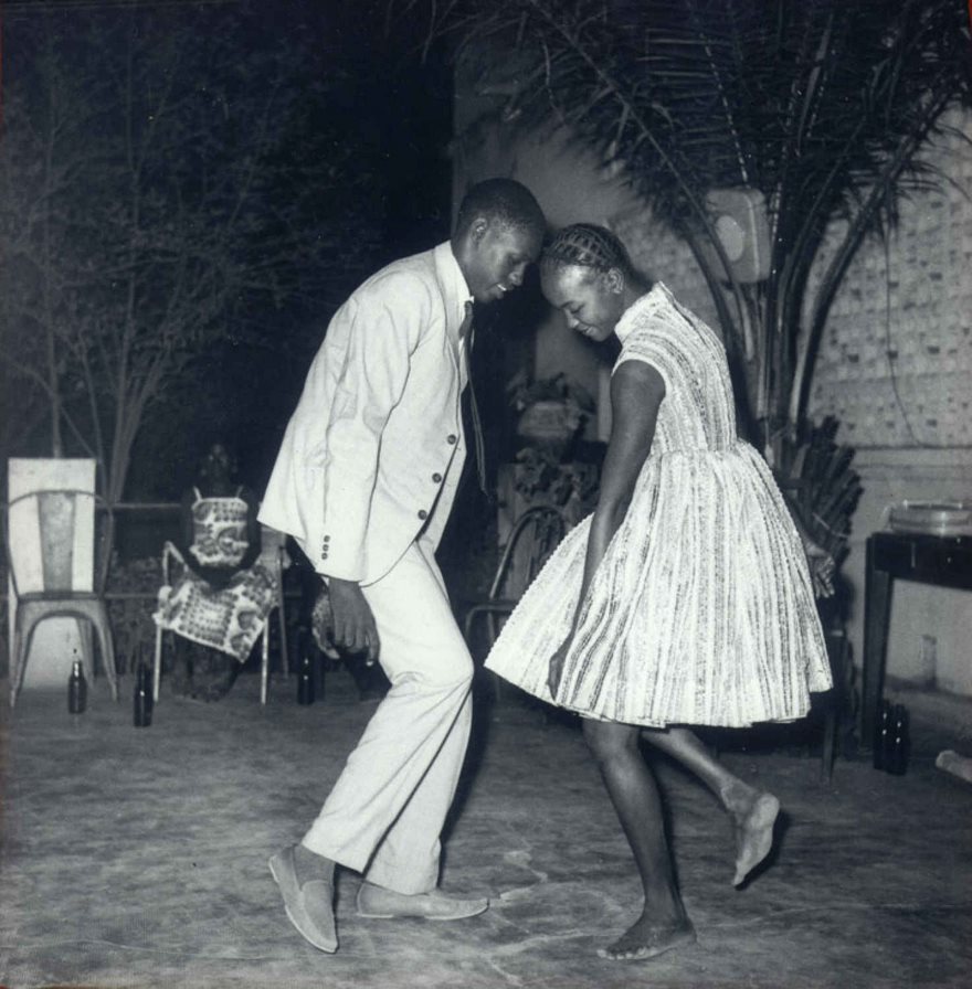 Nuit De Noel, Malick Sidibe, 1963

Malian photographer Malick Sidibé’s life followed the trajectory of his nation. He started out herding his family’s goats, then trained in jewelry making, painting and photography. As French colonial rule ended in 1960, he captured the subtle and profound changes reshaping his nation. Nicknamed the Eye of Bamako, Sidibé took thousands of photos that became a real-time chronicle of the euphoric zeitgeist gripping the capital, a document of a fleeting moment. “Everyone had to have the latest Paris style,” he observed of young people wearing flashy clothes, straddling Vespas and nuzzling in public as they embraced a world without shackles. On Christmas Eve in 1963, Sidibé happened on a young couple at a club, lost in each other’s eyes. What Sidibé called his “talent to observe” allowed him to capture their quiet intimacy, heads brushing as they grace an empty dance floor. “We were entering a new era, and people wanted to dance,” Sidibé said. “Music freed us. Suddenly, young men could get close to young women, hold them in their hands. Before, it was not allowed. And everyone wanted to be photographed dancing up close.”