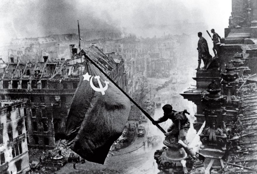 Raising A Flag Over The Reichstag, Yevgeny Khaldei, 1945

“This is what I was waiting for for 1,400 days,” the Ukrainian-born Yevgeny Khaldei said as he gazed at the ruins of Berlin on May 2, 1945. After four years of fighting and photographing across Eastern Europe, the Red Army soldier arrived in the heart of the Nazis’ homeland armed with his ­Leica III rangefinder and a massive Soviet flag that his uncle, a tailor, had fashioned for him from three red tablecloths. Adolf Hitler had committed suicide two days before, yet the war still raged as Khaldei made his way to the Reichstag. There he told three soldiers to join him, and they clambered up broken stairs onto the parliament building’s blood-soaked parapet. Gazing through his camera, Khaldei knew he had the shot he had hoped for: “I was euphoric.” In printing, Khaldei dramatized the image by intensifying the smoke and darkening the sky—even scratching out part of the negative—to craft a romanticized scene that was part reality, part artifice and all patriotism. Published in the Russian magazine Ogonek, the image became an instant propaganda icon. And no wonder. The flag jutting from the heart of the enemy exalted the nobility of communism, proclaimed the Soviets the new overlords and hinted that by lowering the curtain of war, Premier Joseph Stalin would soon hoist a cold new iron one across the land.