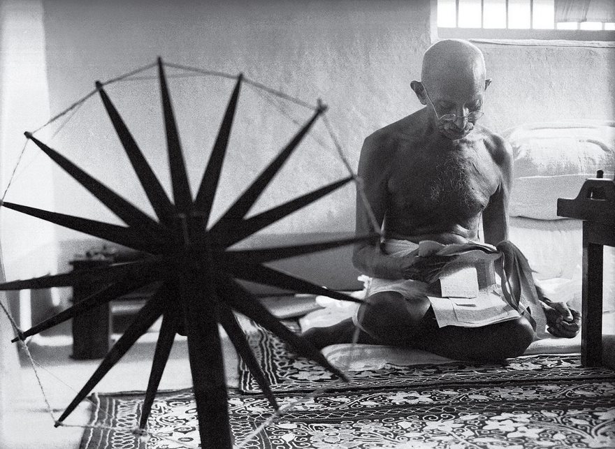 Gandhi And The Spinning Wheel, Margaret Bourke-White, 1946

When the British held Mohandas Gandhi prisoner at Yeravda prison in Pune, India, from 1932 to 1933, the nationalist leader made his own thread with a charkha, a portable spinning wheel. The practice evolved from a source of personal comfort during captivity into a touchstone of the campaign for independence, with Gandhi encouraging his countrymen to make their own homespun cloth instead of buying British goods. By the time Margaret Bourke-White came to Gandhi’s compound for a life article on India’s leaders, spinning was so bound up with Gandhi’s identity that his secretary, Pyarelal Nayyar, told Bourke-White that she had to learn the craft before photographing the leader. Bourke-White’s picture of ­Gandhi reading the news alongside his charkha never appeared in the article for which it was taken, but less than two years later life featured the photo prominently in a tribute published after ­Gandhi’s assassination. It soon became an indelible image, the slain civil-­disobedience crusader with his most potent symbol, and helped solidify the perception of Gandhi outside the subcontinent as a saintly man of peace.