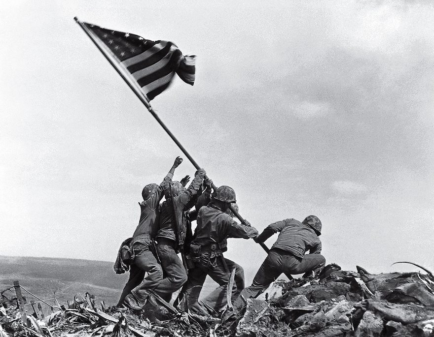 Flag Raising On Iwo Jima, Joe Rosenthal, 1945

It is but a speck of an island 760 miles south of Tokyo, a volcanic pile that blocked the Allies’ march toward Japan. The Americans needed Iwo Jima as an air base, but the Japanese had dug in. U.S. troops landed on February 19, 1945, beginning a month of fighting that claimed the lives of 6,800 Americans and 21,000 Japanese. On the fifth day of battle, the Marines captured Mount ­Suribachi. An American flag was quickly raised, but a commander called for a bigger one, in part to inspire his men and demoralize his opponents. Associated Press photographer Joe Rosenthal lugged his bulky Speed Graphic camera to the top, and as five Marines and a Navy corpsman prepared to hoist the Stars and Stripes, Rosenthal stepped back to get a better frame—and almost missed the shot. “The sky was overcast,” he later wrote of what has become one of the most recognizable images of war. “The wind just whipped the flag out over the heads of the group, and at their feet the disrupted terrain and the broken stalks of the shrubbery exemplified the turbulence of war.” Two days later Rosenthal’s photo was splashed on front pages across the U.S., where it was quickly embraced as a symbol of unity in the long-fought war. The picture, which earned Rosenthal a Pulitzer Prize, so resonated that it was made into a postage stamp and cast as a 100-ton bronze memorial.