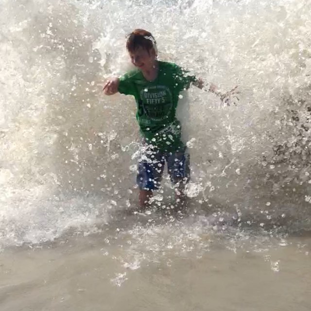 My son at the beach getting hit by waves