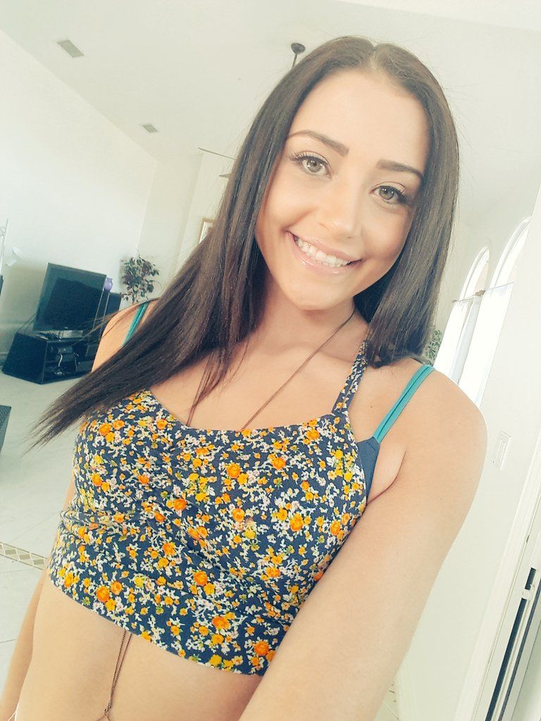Super cute porn star Avi Love taking a selfie while wearing a flower pattern top.
