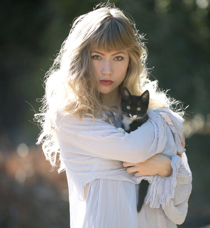 Ultra babe porn star Ivy Wolfe wearing a silky long sleeve shirt while holding a black and white kitten.