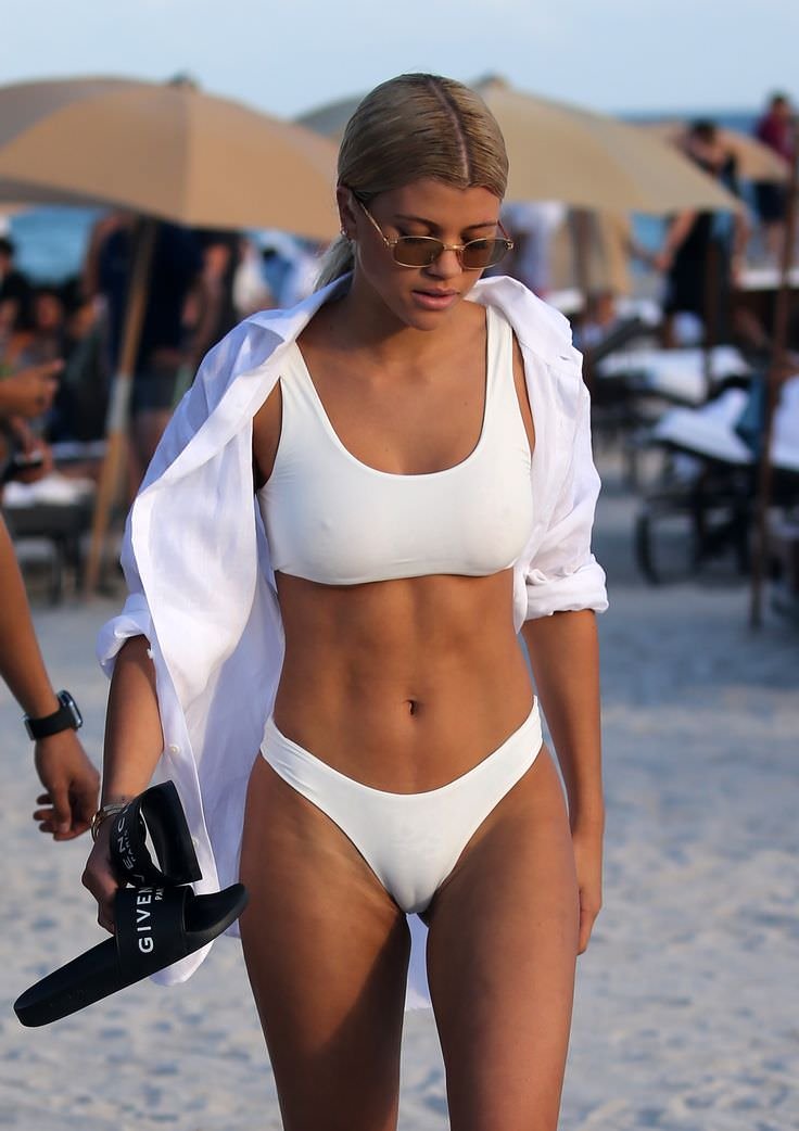 Celebrity Sophia Richie on a beach wearing a white swimsuit and a white shi...