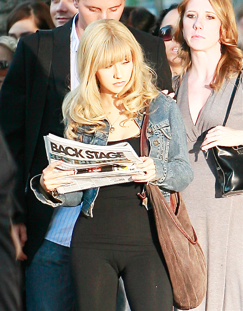 Pop music celebrity Christina Aguilera holding a newspaper and wearing tight black yoga pants showing visible camel toe. 