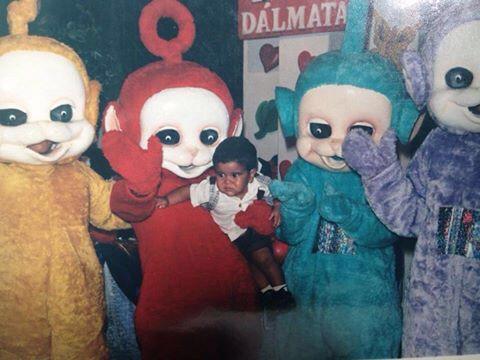 A disturbing photo of a baby being held by people dressed as Teletubbies. 