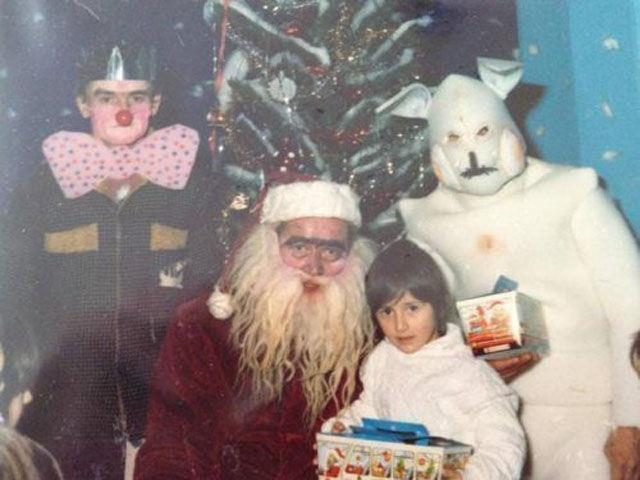 A weird photo of a kid sitting on a strange looking Santa's lap.