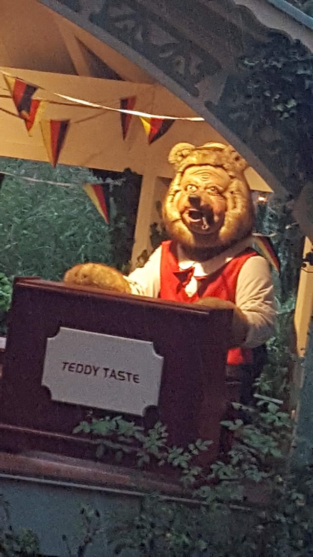A weird image of a bear behind a podium that says "Teddy Taste"