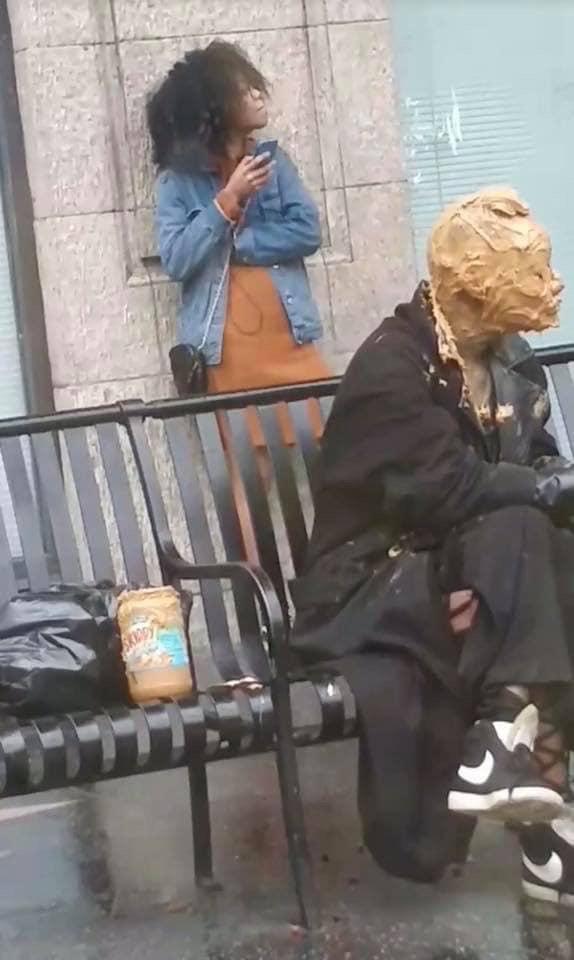 A strange photo of a lady at a bus stop with peanut butter on her face.