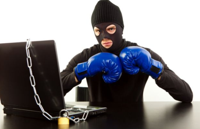 A strange stock image of a burglar in front of a computer wearing blue boxing gloves.