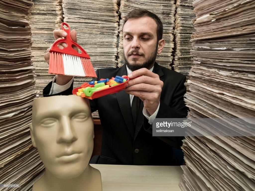 A WTF stock image from getty images of a man sweeping colorful plastic pieces into a fake head.