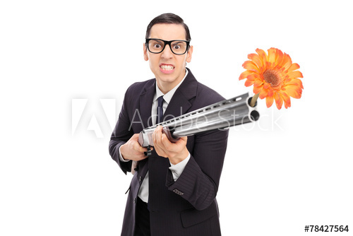 A disturbing stock photo of a man holding a shotgun with a flower coming out of it. 