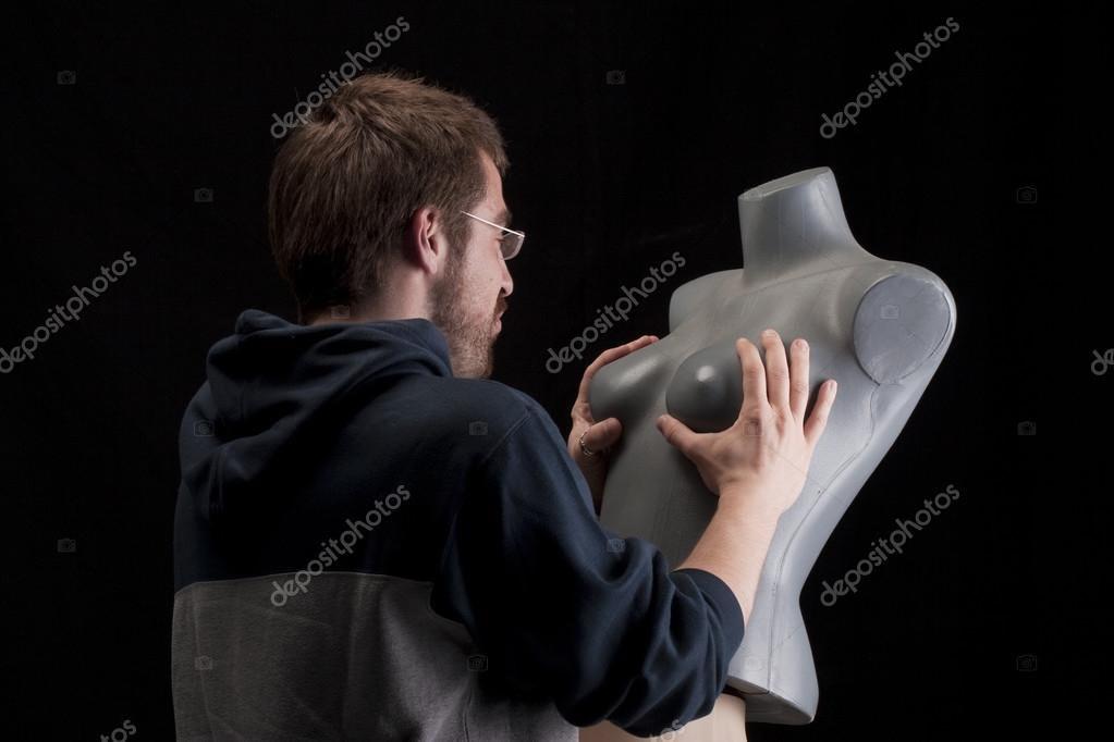 A disturbing stock image of a man holding the breasts of a mannequin. 